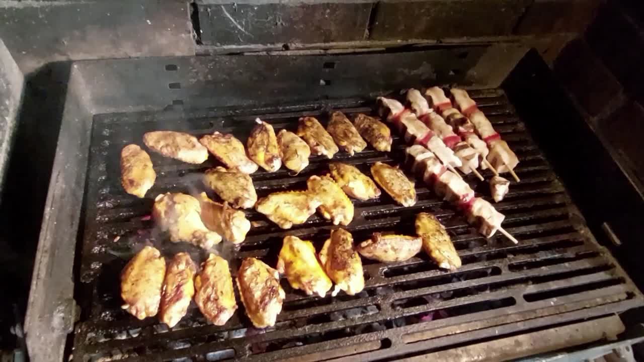 alitas de pollo y brochetas a la parrilla de carbón asado en malla caliente y saliendo humo