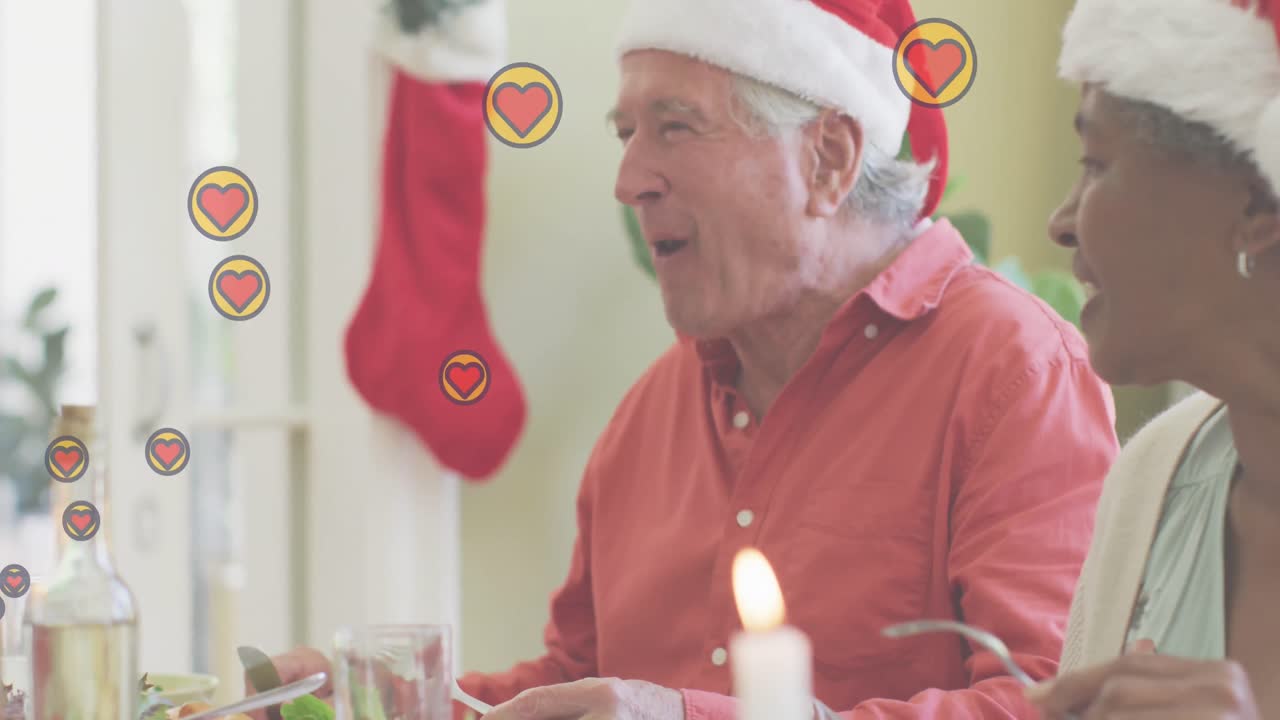 Animação de corações sobre amigos diversos idosos sentados à mesa no Natal
