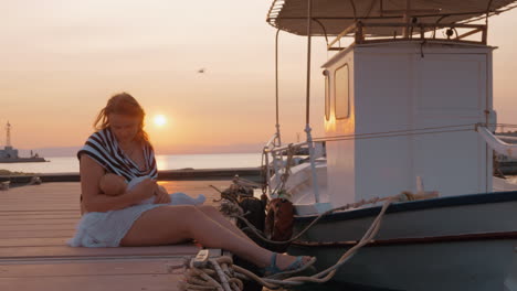 madre amamantando al bebé en el muelle al atardecer