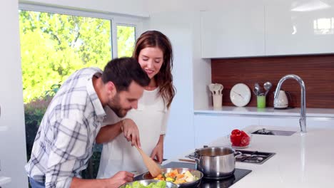 Hombre-Feliz-Alcanzando-A-Su-Esposa-Mientras-Ella-Cocina