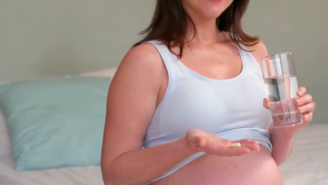 pregnant woman holding pills and glass of water