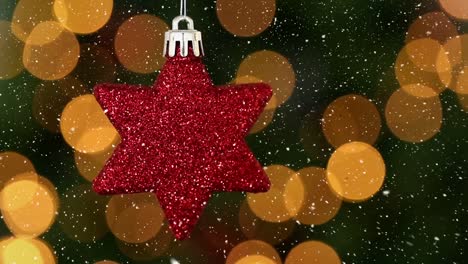 animation of snow falling over red star christmas bauble decoration