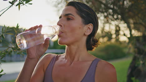 athletic lady renewing water balance intense workout in sunrise park closeup