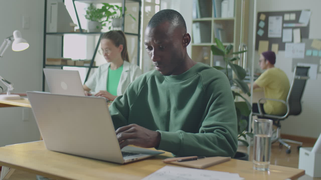 Young Black Man Working on Laptop in Open Space Office