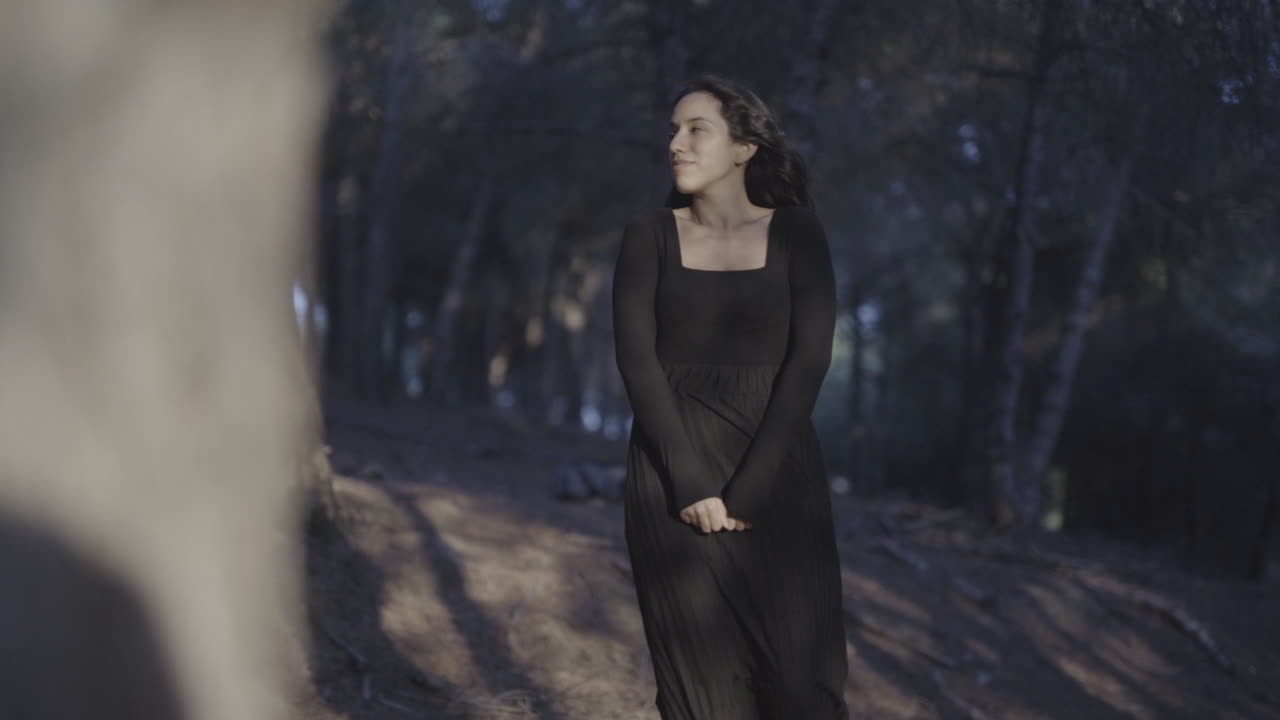 Affascinante modella spagnola che posa con naturalezza vestita di nero nel bosco.