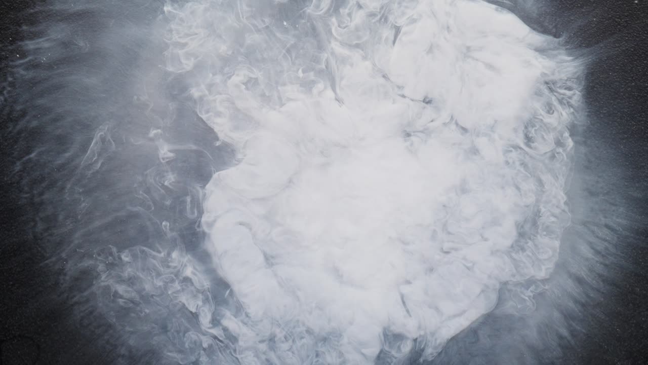 Swirling white alcohol ink forming clouds in liquid, macro abstract with soft textures