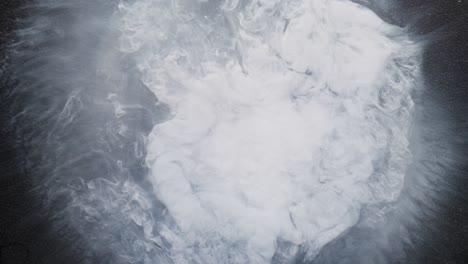 swirling white alcohol ink forming clouds in liquid, macro abstract with soft textures