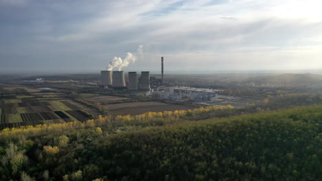 smoke and steam from the industrial coal power plant in the distance. drone going up slowly
