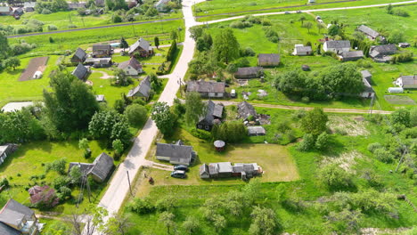 aerial view of countryside homes in suburbs of small lithuanian town, road, houses and green land on sunny summer day