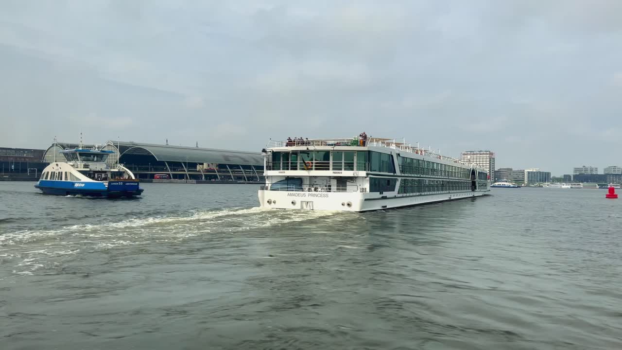 암스테르담 에 있는 네덜란드 의 이지 강 에 있는 크루즈 선박 과 공공 페리 를 지나가는 모습