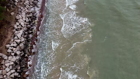 Luftaufnahme-Eines-Felsigen-Strandes-Mit-Tosenden-Wellen,-Wobei-Das-Wasser-Türkis,-Weiß-Und-Braun-Erscheint