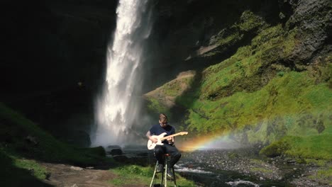 man playing guitar in front of a beautiful waterfall in iceland-23