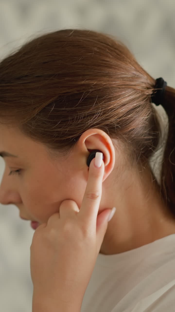 mujer se pone auriculares corriendo en casa de cerca. mujer atlética usa auriculares inalámbricos para escuchar música haciendo ejercicio en el gimnasio doméstico. estilo de vida de fitness
