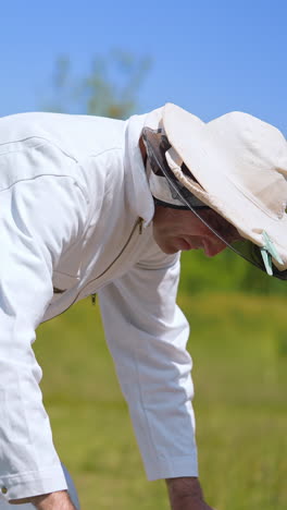 beekeeper in uniform working with beehives. agricultural honeycombs beekeeping. vertical video