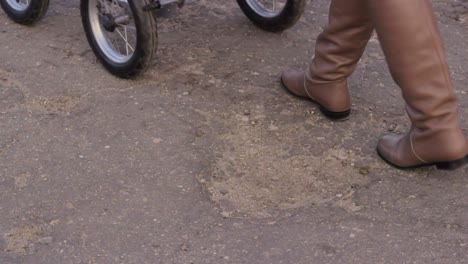 Low-Close-up-of-wheels-of-baby-stroller-riding-on-bad-condition-asphalt