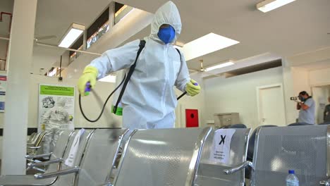 dos soldados con equipo de protección desinfectan las sillas de un hospital después de la contaminación por covid19.