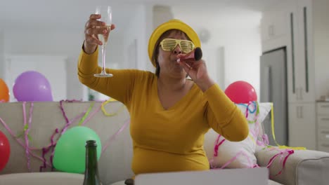 happy african american senior woman raising champagne glass making new year's eve laptop video call