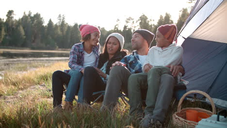 Parents-and-two-children-relaxing-outside-tent-on-camping-trip