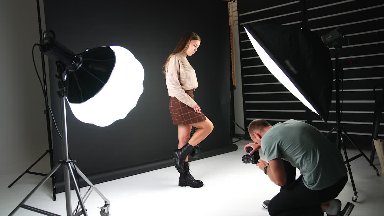 Girl posing in front of camera demonstrating fashionable footwear and bag. Backstage of a photographer working in the studio.