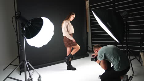 girl posing in front of camera demonstrating fashionable footwear and bag. backstage of a photographer working in the studio.