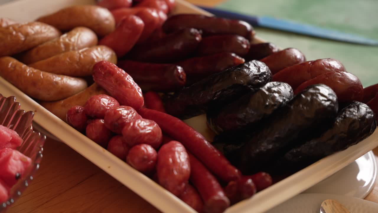 mixed grilled sausages arranged on platter with fresh fruit nearby