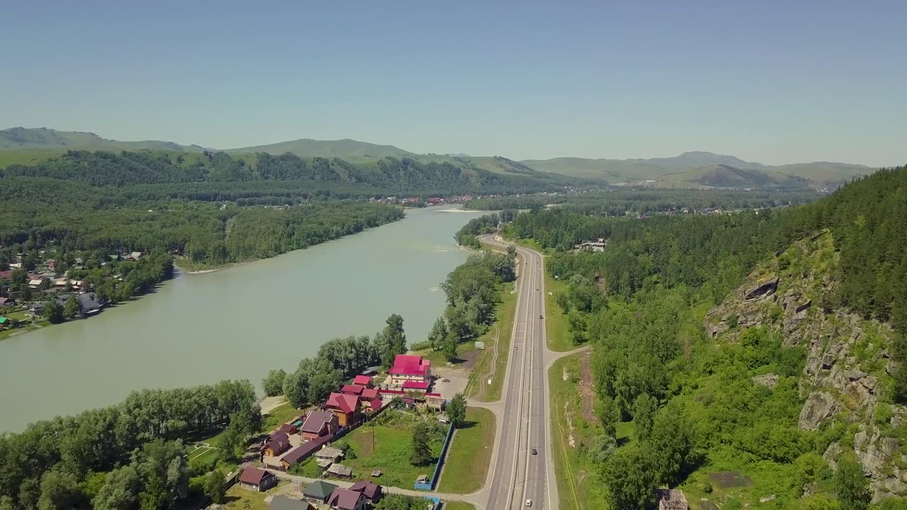 Vista aerea: autostrada, roccia, montagna, fiume turchese e città turistica.