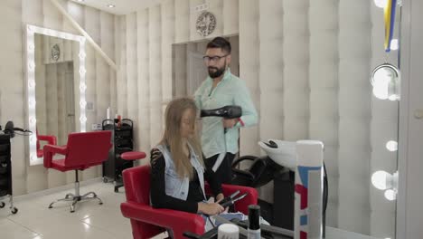 el peluquero profesional sopla laca en el cabello del modelo con un secador de cabello