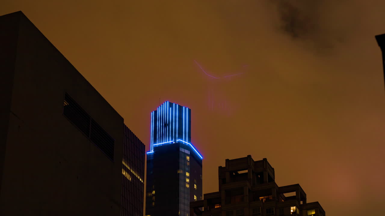 noche de la ciudad con nubes naranjas contaminación lumínica pasando por edificios altos iluminados con led azul lapse de tiempo