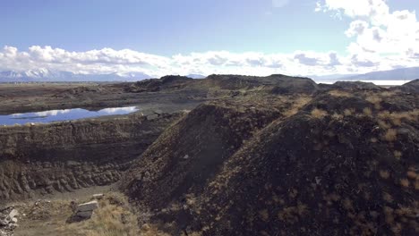 an aerial drone shot flying past the catch pond and slag heap from the former geneva steel mill