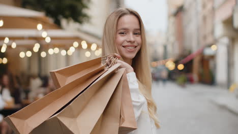 a happy young woman with shopping bags in a city street.