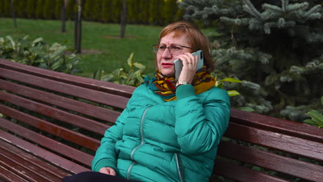 una mujer mayor hablando por teléfono en el parque.