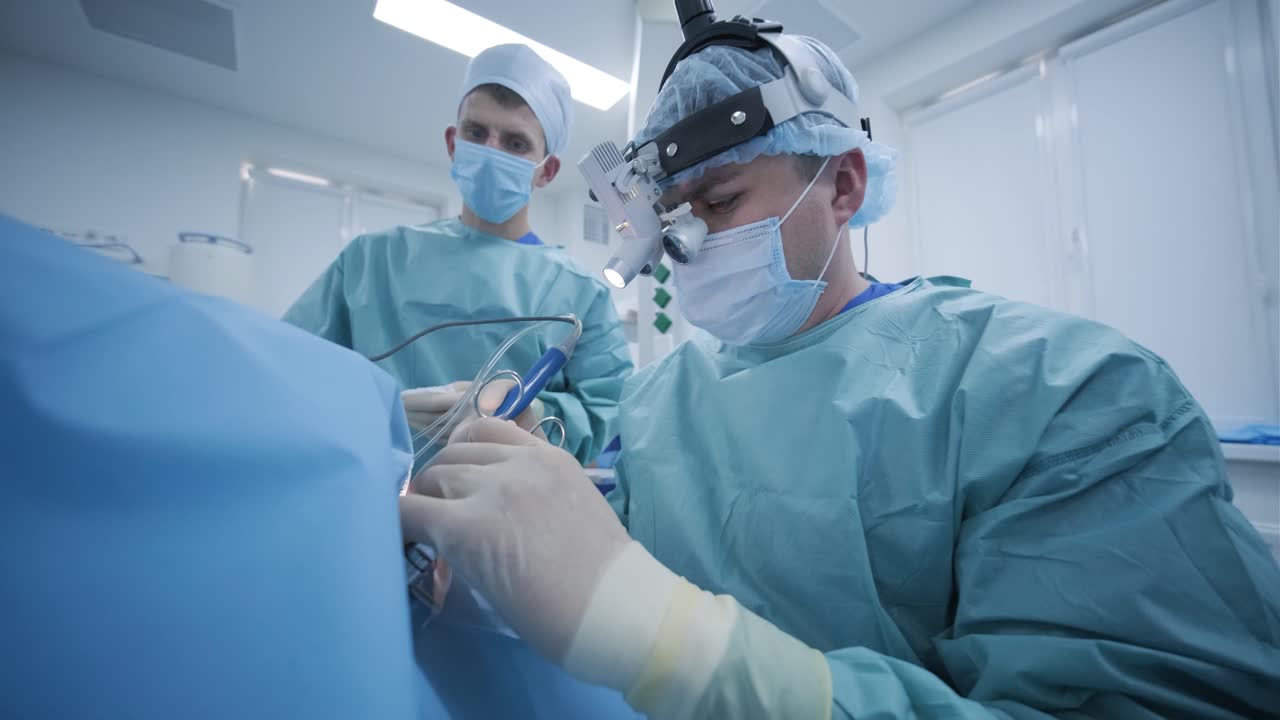 операция по удалению миндалин под глубокой анестезией, хирург использует новейшие устройства, метод холодной плазмы, разрезает отеки в горле, врач работает с новым зондом, медицинской фарой, хирургическими лупами