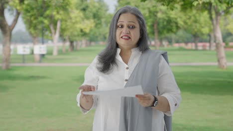 happy old indian woman discussing reports in park