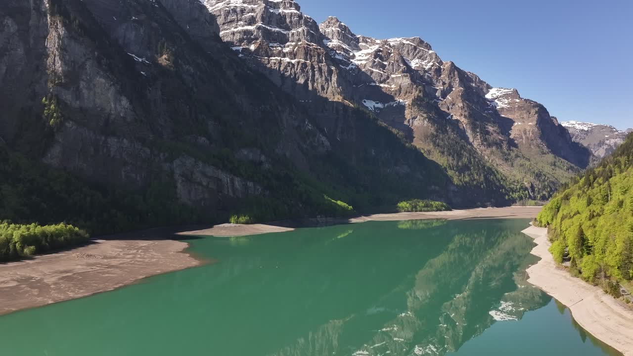 Aerial view of Klöntalersee in Klöntal Valley, Glarus, Switzerland. Stunning turquoise alpine lake surrounded by rugged mountains and lush green forest