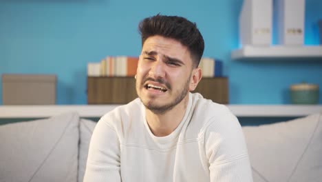 un joven llorando en casa.