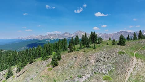 Aerial-over-the-trees-and-hills-of-Cottonwood-Pass-with-the-Rocky-Mountains-in-the-background,-Colorado,-USA