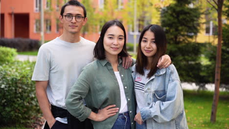 야외에 서있는 동안 웃 고 카메라를 찾고 세 젊은 일본 친구의 그룹