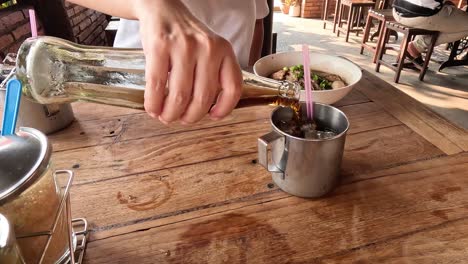 pouring and mixing a drink with ice and herbs