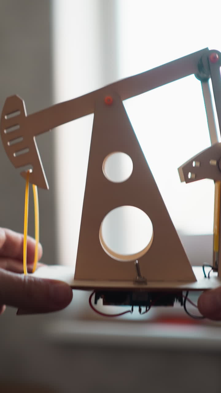 pov de persona levantando un modelo de bomba de aceite motorizado al nivel de la ventana en un escritorio de trabajo, comprobando la electrónica