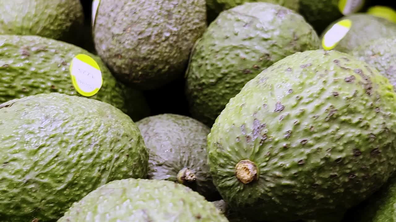 많은 익은 아보카도가 프레임을 채우고, 초록색과 갈색 색조의 텍스처 된 배경을 만니다. 아마도 멕시코 슈퍼마켓에서 구매할 준비가되어 있습니다.