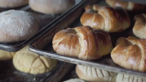 close-up of multiple trays filled with assorted baked pastries cooling on racks inside a bakery