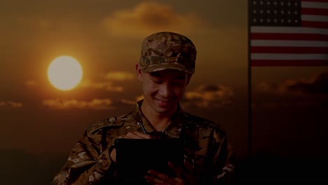 close up of asian man soldier taking note on a tablet while standing with flag of the united states, sunset time