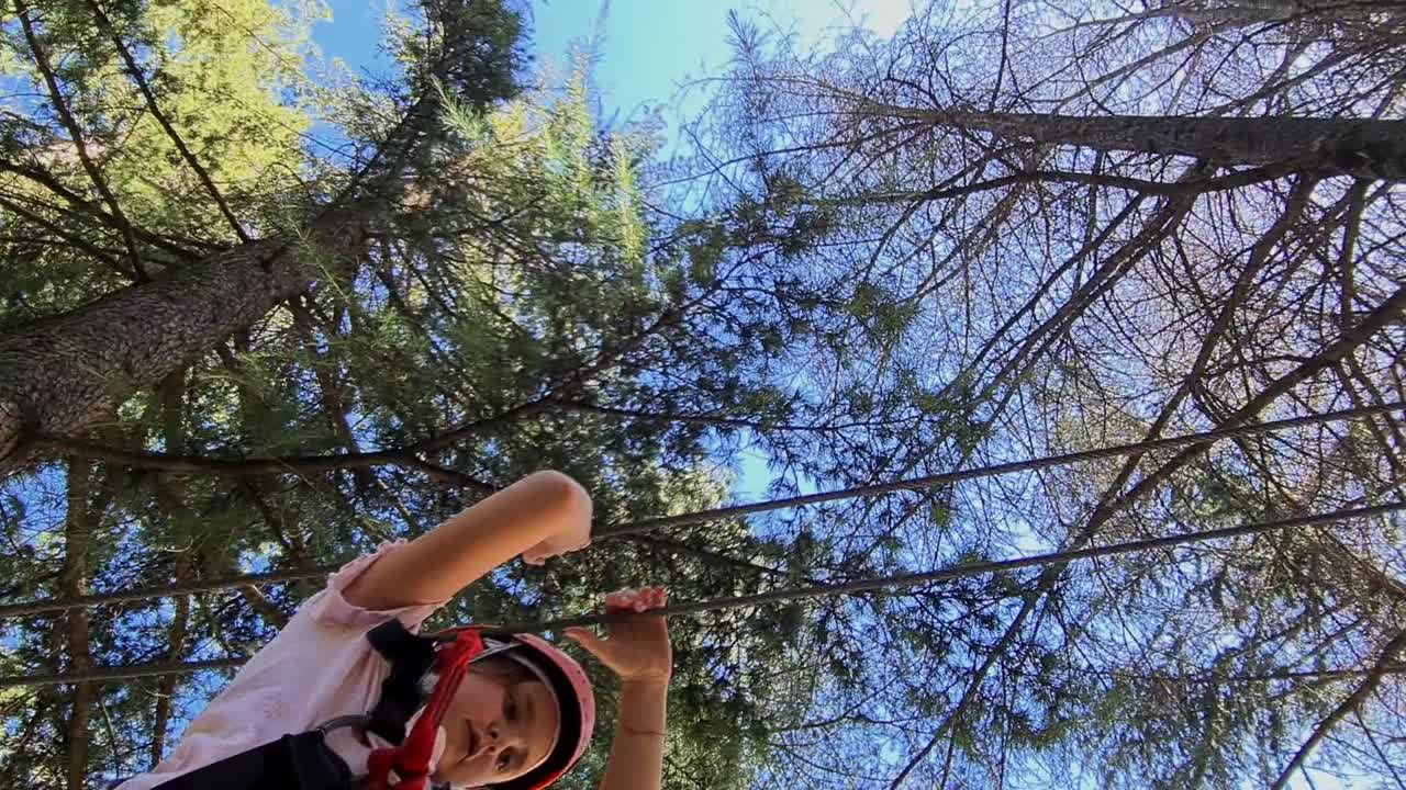 niña caucásica con arnés divirtiéndose en el parque de aventuras