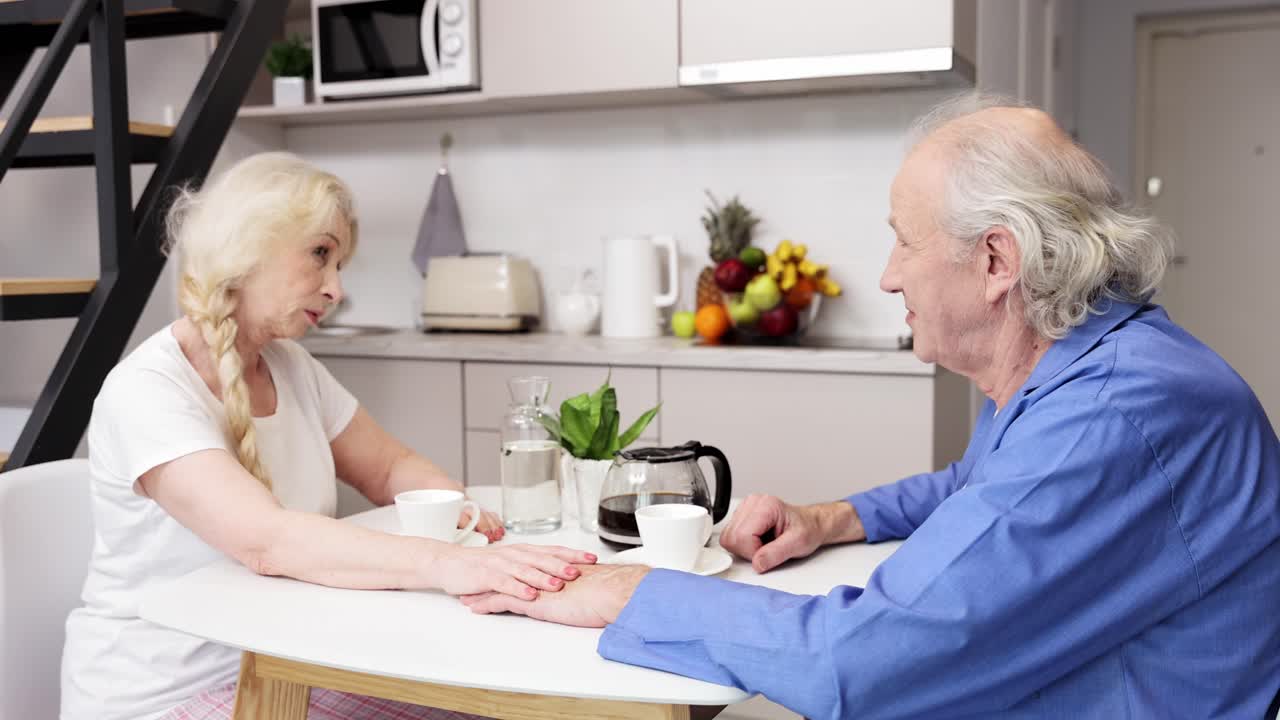 주방 에서 커피 를 마시고 있는 노인 부부