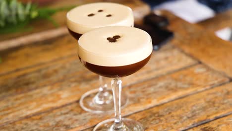 three espresso martinis with coffee bean garnish on a wooden table, captured in warm lighting with a shallow depth of field