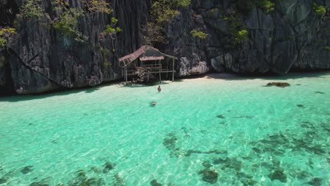video de drone de 4k de una pareja nadando en las impresionantes aguas azules cristalinas en la playa banal mientras están en un viaje en barco desde coron en palawan, filipinas