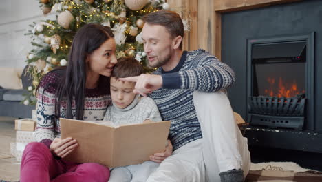 family reading a book by the christmas tree