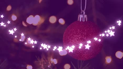 Glowing-star-light-decorations-against-close-up-of-hanging-bauble-on-christmas-tree