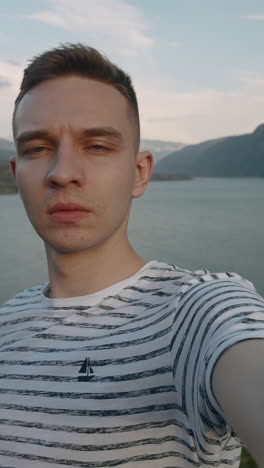 man taking selfie by a lake with mountains