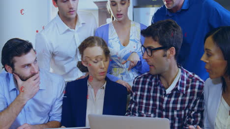 team brainstorming business strategy around laptop, showcasing animated financial charts and icons